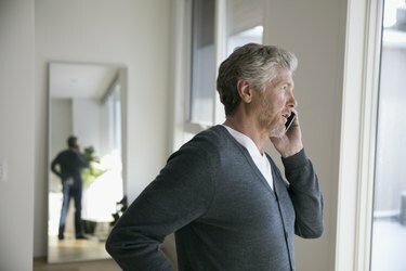 Възрастен мъж говори по мобилен телефон, гледа през прозореца
