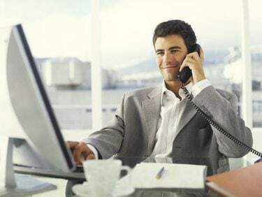 Jaunas verslininkas, naudojantis kompiuteriu ir telefonu