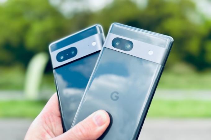 Google Pixel 7 og Pixel 7a holdes i en persons hånd.