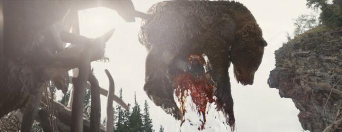 Delno zakrit vesoljec plenilec drži mrtvega medveda visoko v prizoru iz filma Prey.