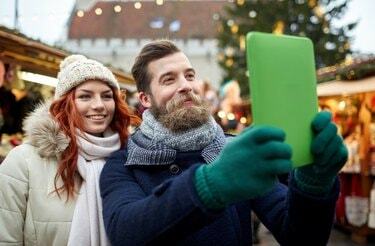 pāris, kas uzņem selfiju ar planšetdatoru vecpilsētā