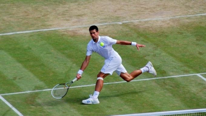 Novak Djokovic lovește o minge la Wimbledon.