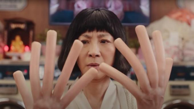 Michelle Yeoh kijkt naar haar hotdogvingers in 'Everywhere All at Once'.