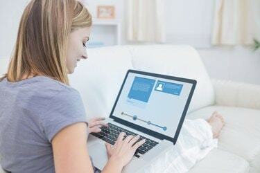 Женщина сидит на диване и проверяет свой профиль в социальных сетях