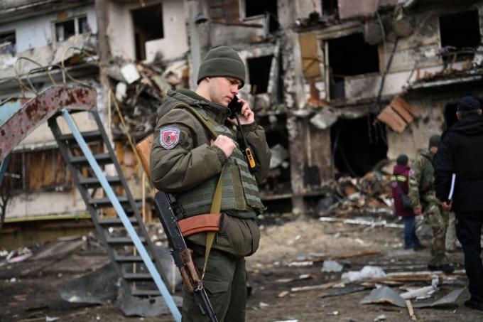 Un militaire ukrainien parle sur son smartphone devant un immeuble résidentiel endommagé de la rue Koshytsa, une banlieue de la capitale ukrainienne Kiev, où un obus militaire aurait été touché.