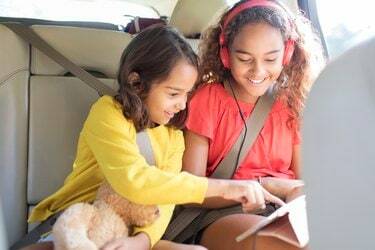 الأخوات يستخدمن الكمبيوتر اللوحي الرقمي في المقعد الخلفي للسيارة