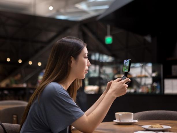 Mulher jogando em um smartphone com GeForce Now em uma cafeteria.