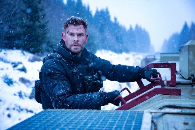 Chris Hemsworth hält sich in Extraction 2 am Schild eines Zuges fest.