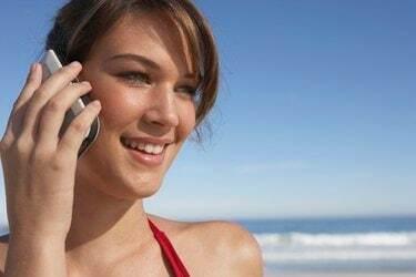 Mladá žena pomocí mobilního telefonu, venku, s úsměvem, detail
