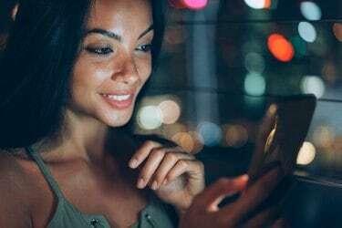 Gadis manis menggunakan ponsel pintar di malam hari