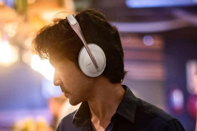 Ein Mann mit Bose 700-Kopfhörern vor einem stimmungsvollen Hintergrund.