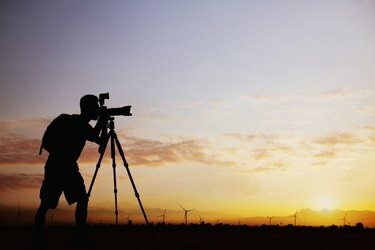 Silhueta moškega, ki fotografira s fotoaparatom ob sončnem zahodu z dramatičnim nebom