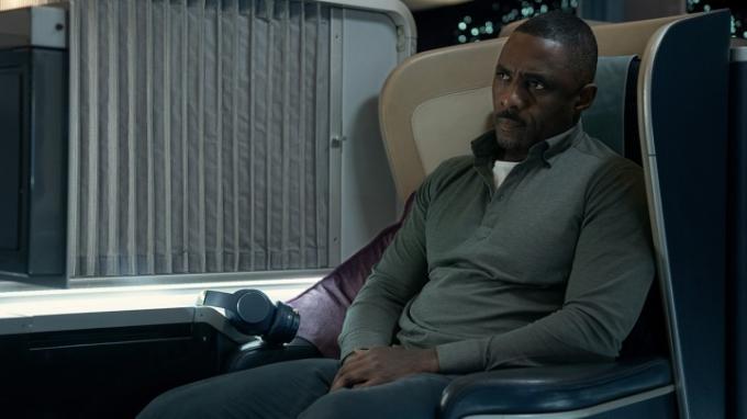 Idris Elba som Sam, der sidder på et flysæde i en scene fra Hijack på Apple TV+.
