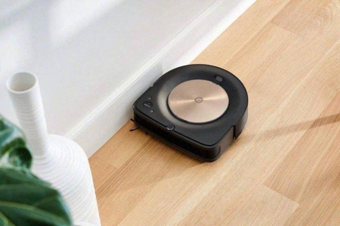 Robotten iRobot Roomba S9 Plus støvsuger gulvet nær væggen.