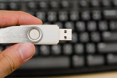 USB-mälupulk käes hoidmisega klaviatuuri taustal