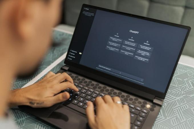 Человек печатает на ноутбуке, на котором отображается веб-сайт генеративного ИИ ChatGPT.