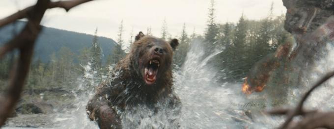 Un oso corriendo por el agua hacia un alienígena Depredador encubierto en una escena de Prey.