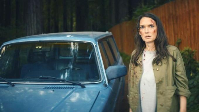 Winona Ryder berdiri di samping mobil biru di Gone in the Night.