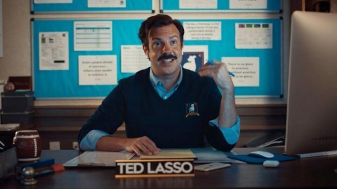 Ted sedí u svého stolu v Ted Lasso.
