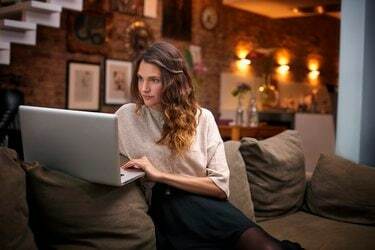 Žena pomocí přenosného počítače na gauči doma