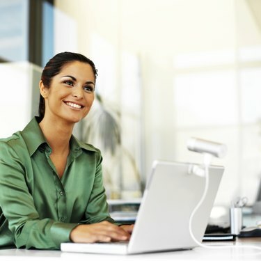 امرأة شابة تبتسم أثناء استخدام الكمبيوتر المحمول