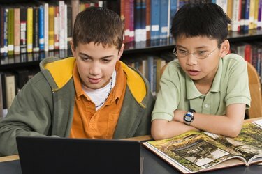 Chlapci pomocí přenosného počítače v knihovně