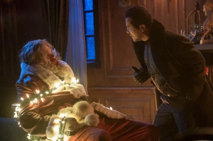 デヴィッド・ハーバーはサンタクロースの格好をしてクリスマスイルミネーションで縛られ、ジョン・レグイザモが彼に向かって叫ぶ。