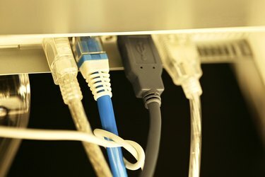 Bir dizüstü bilgisayarın arkasındaki bağlantı noktalarına takılı ethernet ve firewire kablolarının yakından görünümü.