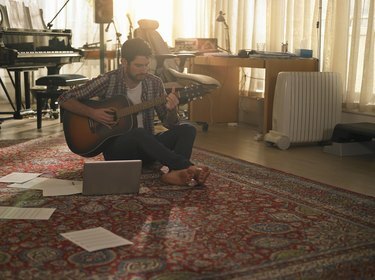Mężczyzna grający na gitarze obok laptopa