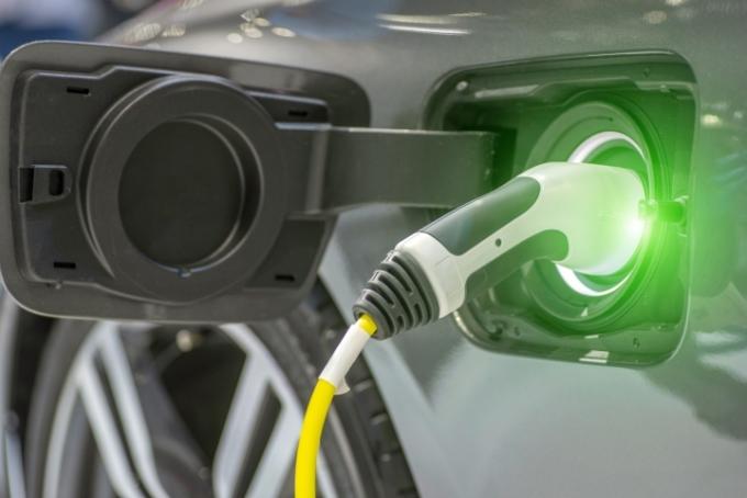 Close-up van het oplaadstation voor hybride auto's met voeding aangesloten op een elektrische auto die wordt opgeladen.