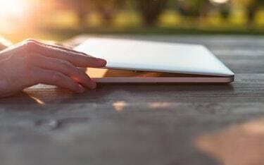 Uomo che apre il suo laptop su un tavolo di legno