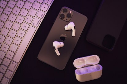 열린 충전 케이스가 근처에 있는 iPhone 위에 올려놓은 AirPods Pro.