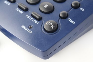 Tlačítko reproduktoru na moderním pevném telefonu v modré barvě