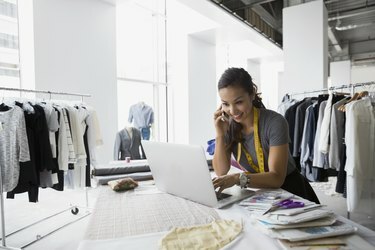 Créateur de mode parlant au téléphone portable et utilisant un ordinateur portable