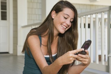 Усмихната тийнейджърка използва мобилен телефон