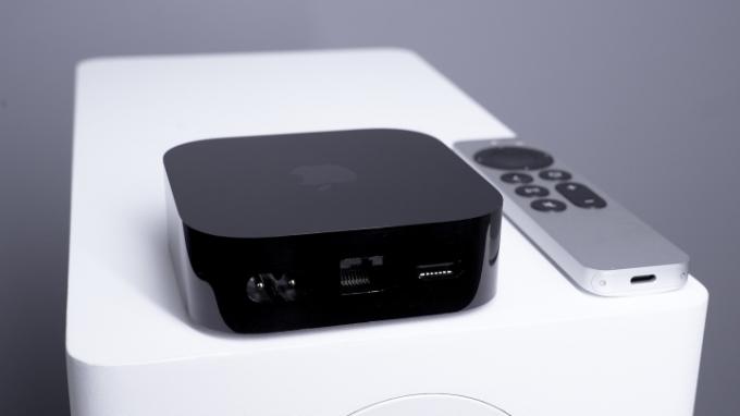 Set bagfra af et Apple TV 4K, der viser gigabit ethernet-port, HDMI-port og strømport, med Siri-fjernbetjeningen ved siden af ​​i baggrunden.